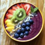 - 2 packets (100g each) frozen acai puree - 1 ripe banana, sliced - 1 cup unsweetened almond milk (or any milk of choice) - 1 tablespoon almond butter - 1 tablespoon honey or agave syrup (adjust to taste) For the acai smoothie bowl, you need fresh and frozen ingredients. The frozen acai puree gives your bowl its rich, deep color. Bananas add natural sweetness and creaminess. Use almond milk for a smooth texture that blends well. Almond butter brings healthy fats and a nutty taste. Honey or agave syrup can sweeten the mix, so adjust it based on your liking. - 1/2 cup granola - 1/4 cup unsweetened shredded coconut - Fresh fruits for topping (sliced strawberries, blueberries, kiwi, or mango) - Chia seeds for garnish - Fresh mint leaves for garnish The toppings are what make your acai bowl fun and tasty! Granola adds crunch, while shredded coconut gives a tropical feel. Fresh fruits not only look good but also add more flavor. Chia seeds are great for extra nutrition, and mint leaves add a fresh touch. You can mix and match your toppings based on what you enjoy. Check out the Full Recipe for step-by-step details! Start by preparing your blender. Ensure it is clean and ready to use. Then, measure out your ingredients. You need: - 2 packets (100g each) frozen acai puree - 1 ripe banana, sliced - 1 cup unsweetened almond milk (or any milk of choice) - 1 tablespoon almond butter - 1 tablespoon honey or agave syrup (adjust to taste) Having everything ready makes the next steps smooth and easy. Now, combine the main ingredients in your blender. Add the frozen acai puree, sliced banana, almond milk, almond butter, and honey or agave syrup. Blend on high speed until the mix is smooth and creamy. If the smoothie is thick, add more almond milk bit by bit until you like the texture. After blending, taste your acai mixture. If it needs sweetness, add more honey or agave syrup. Blend briefly to mix in the added sweetness. Carefully pour the acai smoothie mixture into a large bowl. Aim for even distribution for a nice look. Next, layer your toppings. Start with granola on top, then add your fresh fruits like strawberries, blueberries, kiwi, or mango. Sprinkle unsweetened shredded coconut over the fruits. Finish with a dash of chia seeds for a nice touch. To make it beautiful, garnish with fresh mint leaves. This adds a pop of green and a lovely aroma. Serve your Acai Bliss Smoothie Bowl right away with a spoon. Enjoy the vibrant flavors and nutrition! To get the right thickness for your acai smoothie bowl, start by adjusting the almond milk. If your mix is too thick, add more almond milk slowly. This way, you can control the texture. When blending, use short bursts. This helps create a creamy, smooth blend without over-mixing. To make the smoothie bowl sweeter, try adding more honey or agave syrup. Just blend a little more after adding. If you want alternatives to honey, consider maple syrup or mashed ripe banana. These options add sweetness without using extra syrup. When topping your bowl, get creative! Arrange granola in a line, then add fresh fruits in colorful patterns. This not only looks good but tastes great too. For garnishing, sprinkle chia seeds for a nice touch and add fresh mint leaves. They make your bowl pop with color and flavor. {{image_4}} You can make your acai smoothie bowl unique by swapping out flavors. Use different fruits to change the taste. Instead of banana, try mango or even spinach for a green kick. For nut butters, if almond is not your favorite, peanut butter works well. Each option opens a new world of flavor. If you need vegan options, you can easily make this dish plant-based. Replace honey with agave syrup or maple syrup. For nut-free diets, consider sun butter instead of almond butter. Use gluten-free granola if you avoid gluten. This way, everyone can enjoy a tasty bowl. Using seasonal fruits can make your bowl fresh and fun. In summer, add ripe peaches or fresh berries. In winter, consider oranges or pomegranate to brighten your dish. Change your toppings based on what's available. This not only enhances flavor but also keeps it exciting. Enjoy making your acai bowl special! To store your acai smoothie bowl leftovers, place the bowl in the fridge. It stays fresh for up to 24 hours. Cover it with plastic wrap or a lid to prevent drying out. If you want to freeze the smoothie base, pour it into ice cube trays. This method keeps your acai mixture fresh for up to three months. Once frozen, transfer the cubes to a freezer bag. This makes it easy to blend later. When reheating or refreshing leftover bowls, avoid the microwave. Instead, blend your smoothie base with a splash of almond milk. This helps restore its creamy texture. To maintain the freshness of toppings, store them separately. Keep fruits in a sealed container in the fridge. Granola and coconut should stay in airtight bags. This way, they stay crunchy and flavorful. An acai smoothie bowl is a thick blend made from acai berries. It is often topped with fruits, nuts, and seeds. These bowls are popular for breakfast or as a snack. They are vibrant, tasty, and packed with nutrients. Acai bowls are fun to make and easy to enjoy. Many people love them for their beauty and health benefits. Yes, you can easily make this recipe vegan. Instead of almond butter, use peanut or sunflower seed butter. For sweeteners, replace honey with agave syrup or maple syrup. Use any plant-based milk like oat or soy milk. These swaps keep the dish tasty and plant-based. You can customize your smoothie bowl in many ways. Try different fruits, like mango or pineapple, for new flavors. Swap the almond butter for cashew or hazelnut butter. Add protein powder for an extra boost. When it comes to toppings, use nuts, seeds, or your favorite granola. Be creative and make it your own! Acai berries are very healthy. They are high in antioxidants, which help fight free radicals. They can support heart health and improve cholesterol levels. Acai berries may help with weight loss and boost energy. They are also rich in fiber, which aids digestion. Eating acai can contribute to a balanced diet. This blog post covered how to make a delicious acai smoothie bowl. You learned about key ingredients and toppings, plus step-by-step instructions. I shared tips for perfecting your bowl’s texture and sweetness. You also discovered variations for taste and dietary needs. Finally, we discussed storage for any leftovers. Now, you can enjoy this healthy treat anytime. Get creative with your flavors and toppings. Have fun making your own acai bowl!