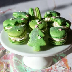 To make these festive Christmas tree cake macarons, you will need: - 1 cup almond flour - 1 &frac34; cups powdered sugar - 4 large egg whites (preferably aged) - &frac14; cup granulated sugar - 1 teaspoon vanilla extract - &frac12; teaspoon peppermint extract - Green gel food coloring These ingredients create the tasty macaron shells. Almond flour gives the macarons their unique texture. Powdered sugar adds sweetness and helps with the smoothness of the shells. The egg whites are key for the meringue, while the sugars help stabilize it. The extracts and food coloring provide that special holiday flavor and look. For the buttercream filling, gather these: - 1 cup unsalted butter, softened - 4 cups powdered sugar - 2 tablespoons heavy cream This creamy filling balances the sweetness of the macarons. The softened butter should be mixed until light and fluffy. Gradually adding powdered sugar creates a smooth texture. The heavy cream helps make the filling airy and easy to spread. To make your macarons extra festive, consider these optional ingredients: - Edible glitter or shimmer sprinkles - Miniature stars or gold sprinkles (for the tree tops) These decorative touches add sparkle and charm. They help your macarons resemble real Christmas trees, making them perfect for holiday gatherings. Use these fun decorations to show off your creativity! {{ingredient_image_2}} To start, preheat your oven to 300&deg;F (150&deg;C). Line two baking sheets with parchment paper. In a bowl, sift together 1 cup of almond flour and 1 &frac34; cups of powdered sugar. This step helps make the shells smooth. Next, in a large mixing bowl, beat 4 large egg whites with a hand mixer on medium speed. Once frothy, gradually add &frac14; cup of granulated sugar. Turn up the speed until you get stiff peaks. This is key for the right texture. Gently fold the sifted almond flour mixture into the egg whites. Do this in three parts to keep the mix airy. Then, add 1 teaspoon of vanilla extract, &frac12; teaspoon of peppermint extract, and green gel food coloring until you reach your desired shade of green. Transfer the macaron batter into a piping bag fitted with a round tip. Pipe small tree shapes onto your lined baking sheets. You can use a template if you want. Once piped, gently tap the sheets on the counter to release any air bubbles. Let the macarons sit at room temperature for 30 to 60 minutes until they form a skin. Now it's time to bake! Place the macaron sheets in your preheated oven. Bake for 15 to 20 minutes. You want them to form feet and not stick to the parchment. After baking, let them cool fully on the sheets. Then, carefully move them to a wire rack to cool completely. While the shells cool, you can make the buttercream. In a medium bowl, beat 1 cup of softened unsalted butter until creamy. Gradually mix in 4 cups of powdered sugar. Add 2 tablespoons of heavy cream to achieve a light and fluffy texture. This buttercream will give your macarons a festive heart. Once the shells and buttercream are ready, it&rsquo;s time to assemble! Pair similar-sized macaron shells. On the flat side of one shell, pipe a generous amount of peppermint buttercream. Top it with another shell to create a sandwich. Repeat until all shells are filled. For the fun part, use more buttercream to add small dots on top. This looks like tree ornaments. Sprinkle edible glitter for that festive sparkle. Finish by placing a mini star or gold sprinkle on top of each macaron tree. Now, you have beautiful Christmas Tree Cake Macarons that are ready to impress! - Sift your dry ingredients: Sifting almond flour and powdered sugar helps avoid lumps. It gives you a smooth macaron shell. - Use room temperature egg whites: Older egg whites whip better. Let them sit out for a few hours. - Fold with care: When mixing the dry ingredients into the egg whites, fold gently. You want to keep air in the batter. - Rest your shells: Let the piped macaron shells sit for 30-60 minutes. This helps form a skin and prevents cracks. - Check your oven: Ovens can vary in temperature. Use an oven thermometer for best results. - Overmixing the batter: This can lead to flat macarons. Stop folding as soon as the batter flows like lava. - Not using a scale: Weighing ingredients gives you accurate measurements. This helps ensure your macarons turn out well. - Skipping the resting step: Don&rsquo;t rush this part. It&rsquo;s key for that perfect shell. - Baking too long: Overbaking makes macarons dry. Check them at 15 minutes. - Create a festive display: Arrange the macarons on a pretty platter. Add some edible glitter or ornaments for fun. - Pair with hot cocoa: These macarons taste great with a warm drink. It adds a cozy touch. - Gift them: Pack them in a nice box. They make great gifts for friends and family. - Use as cake toppers: Place the macarons on top of a cake for a festive look. It adds height and fun! Pro Tips Use Older Egg Whites: Using older egg whites that have been aged in the fridge for a day or two can help achieve better volume and stability in your meringue. Resting Time is Crucial: Allowing the piped macaron shells to rest for 30-60 minutes before baking is essential for forming a skin, which helps create the characteristic &lsquo;feet&rsquo; of the macarons. Check Oven Temperature: Oven temperatures can vary, so it&rsquo;s a good idea to use an oven thermometer to ensure your macarons bake at the correct temperature for the best results. Decorate with Flair: Get creative with decorating your macarons! Use different colored edible glitter and various sprinkles to make each Christmas tree unique and festive. {{image_4}} You can change the flavor of the buttercream to match your taste. Here are some ideas: - Chocolate: Add cocoa powder to create a rich chocolate filling. - Coconut: Mix in shredded coconut for a tropical twist. - Eggnog: Use eggnog flavoring for a holiday classic. - Orange Zest: Add fresh orange zest for a bright, citrus note. Each option gives a new twist to your Christmas Tree Cake Macarons. Decorating your macarons can be fun and creative. Here are some ideas: - Sprinkles: Use colorful sprinkles to mimic ornaments. - Chocolate Drizzle: Drizzle melted chocolate for a festive touch. - Coconut Flakes: Add flakes for a snowy look. - Edible Glitter: Sprinkle edible glitter for some sparkle. These decorations make your macarons stand out at any holiday gathering. Do you want to try different shapes? Here are some fun ideas: - Snowflakes: Pipe snowflake shapes for a winter wonderland theme. - Stars: Create star-shaped macarons to fit the season. - Gingerbread Men: Make gingerbread man shapes for a festive touch. - Candy Canes: Shape macarons like candy canes for a sweet twist. These shapes can add excitement and charm to your holiday treats. To keep your Christmas tree cake macarons fresh, place them in an airtight container. Make sure to layer them carefully with parchment paper in between. This prevents them from sticking together. Store the container in a cool, dry place. Avoid direct sunlight, as it can ruin the texture. You can freeze macarons for up to three months. First, let them cool completely. Then, pack them in a single layer in an airtight bag. Squeeze out all the air before sealing. When you're ready to enjoy, thaw them in the fridge overnight. This keeps them fresh and tasty. Decorated macarons last up to five days at room temperature. If they contain cream filling, eat them within three days. For the best taste, enjoy them fresh. However, if you must store them longer, use the freezer method. This ensures you have festive treats ready for any occasion! Macarons are small, colorful cookies made from almond flour and egg whites. They have a smooth shell and a soft filling. The texture is light and chewy. These treats come in many flavors and colors, making them fun for any event. For our Christmas Tree Cake Macarons, they are shaped like little trees and filled with mint buttercream. Yes, you can use any color you like for the macaron shells! Just add a few drops of gel food coloring to your batter. Mix until you reach your desired shade. For our Christmas Tree Cake Macarons, we use green to mimic a festive tree. You can also mix colors for a fun twist! Cracked macarons often happen due to over-mixing or not resting long enough. To fix this, ensure you fold the batter gently. After piping, let the shells sit until a skin forms. This usually takes 30-60 minutes. If your macarons still crack, check your oven temperature. Too hot can cause issues too. If you need a substitute for almond flour, try using finely ground sunflower seeds. This option works well for those with nut allergies. You can use equal amounts of sunflower seed flour in your recipe. However, keep in mind that the color and flavor may differ slightly. You learned about the key ingredients for macarons and buttercream filling. I shared step-by-step instructions for making the shells and buttercream. We also reviewed tips to avoid common mistakes and discussed festive serving ideas. Flavor and decoration options let you customize macarons for any occasion. Proper storage keeps your treats fresh. With this knowledge, you can create delightful macarons that impress everyone. Enjoy the process, and let your creativity shine!
